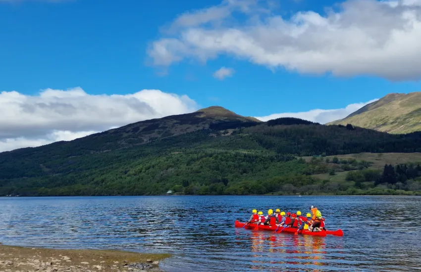 scouts in a canoe on a loch with a hill in the background