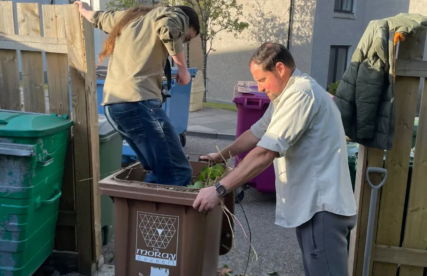 An explorer crushes garden waste in a bin
